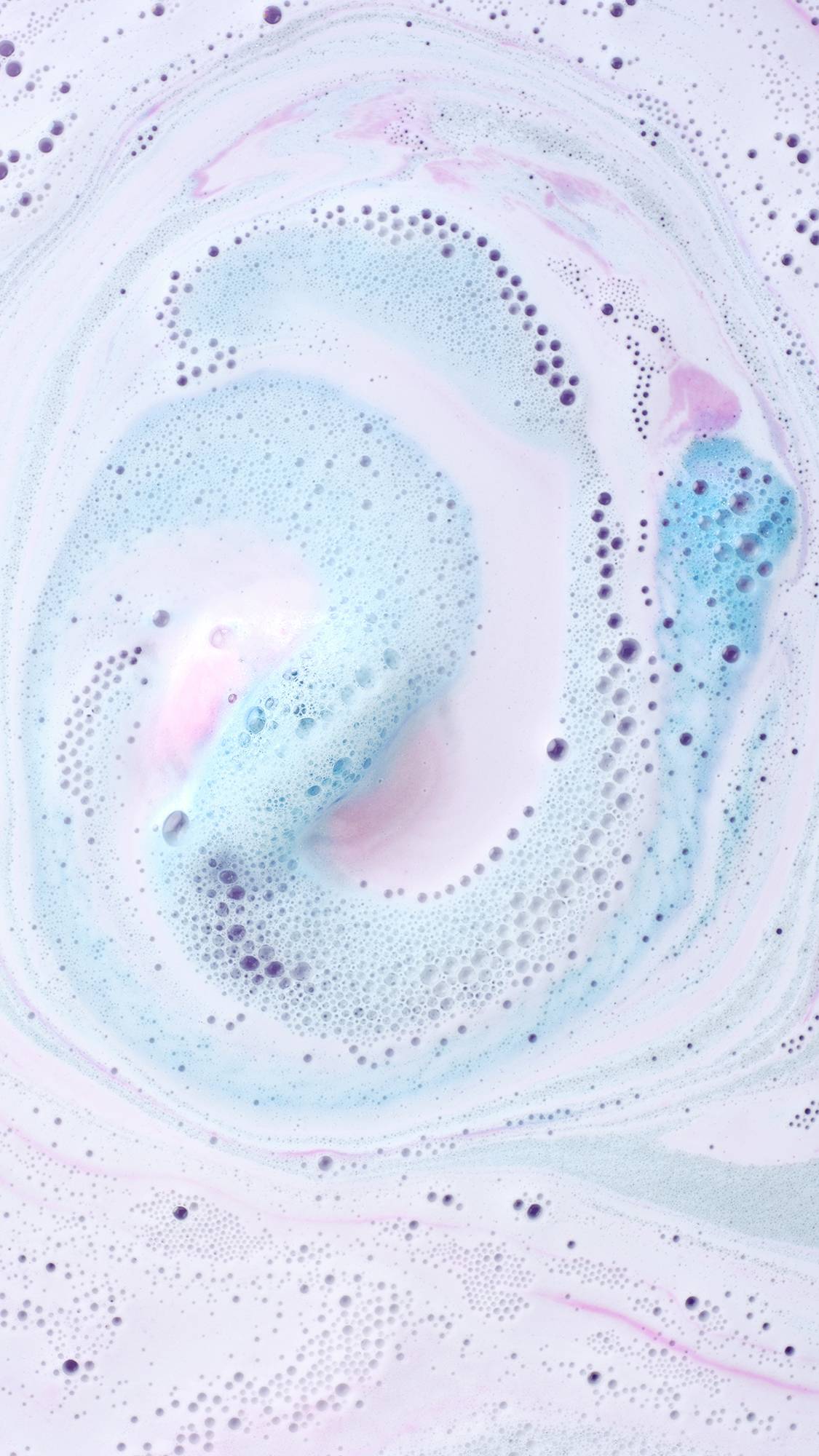 A top-down view of a dissolved Twilight Bath Bomb in water, showing a mesmerizing, milky swirl of pastel blue, lavender, and white foam with tiny bubbles.