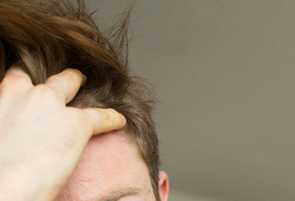 A person ruffles their hand through their hair, creating a volumised look.